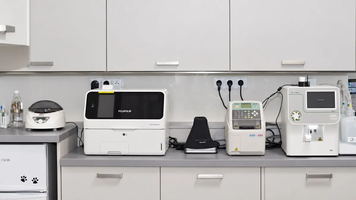 Čelní pohled na laboratorní linku s centrifugou, biochemickým analyzátorem, digitálním mikroskopem a lednicí s motivem tlapek