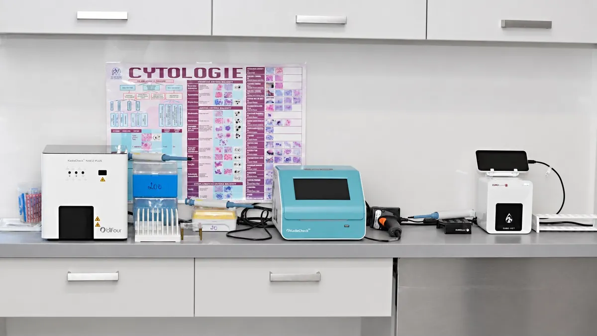 Laboratorní linka s cytologickým plakátem na stěně a několika stolními analyzátory