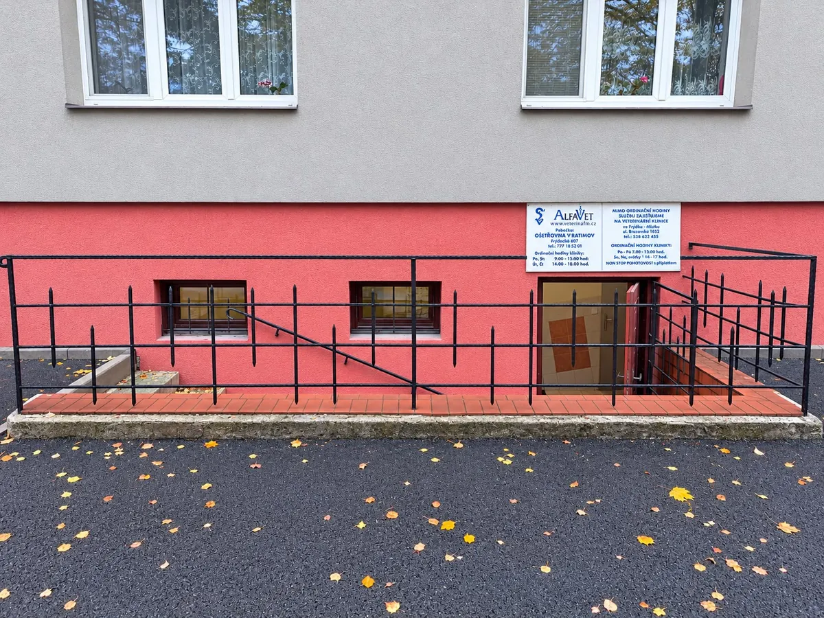 Čelní pohled na vstup do ošetřovny ve Vratimově s červenou fasádou, zábradlím a cedulí